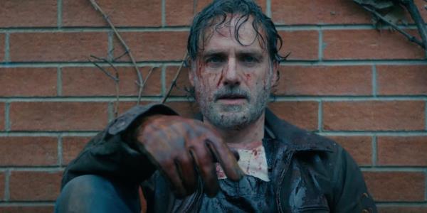 A bloodied Rick Grimes (Andrew Lincoln) sitting against a brick wall in The Walking Dead: The o<em></em>nes Who Live Trailer